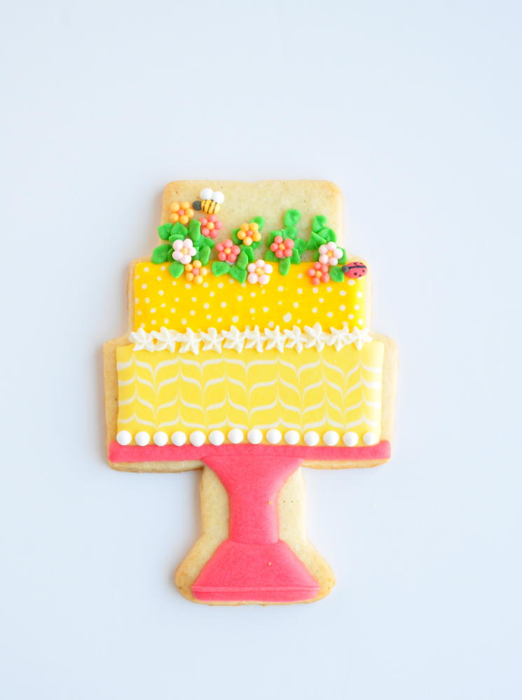 Yellow cake with flowers on pedestal by Jolies Gourmandises